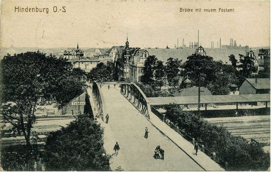 Pocztówka wykonana po zmianie nazwy miasta w 1915 roku na Hindenburg O.-S. Tablica na dworcu nie została jeszcze zmieniona. (Na lewo od mostu)